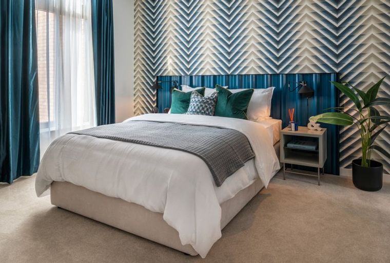 A bedroom with a bed, pillows, curtains, and a nightstand.