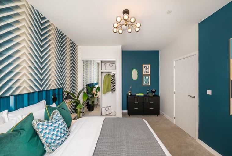 A bedroom with a bed, a dresser, and a geometric accent wall.