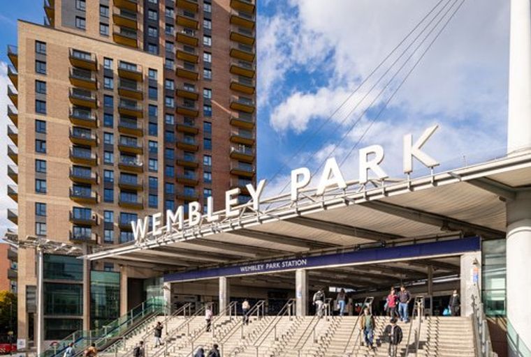 A view of the Wembley Park Station entrance with a modern apartment building in the background.