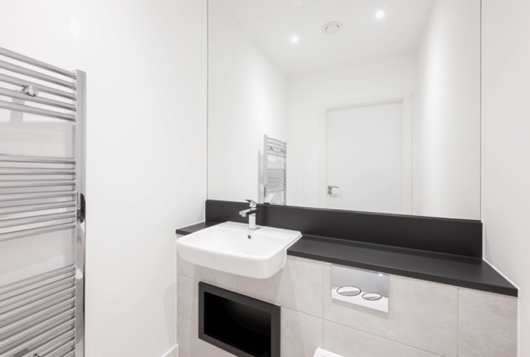 A modern bathroom with a sink, mirror, and towel warmer.