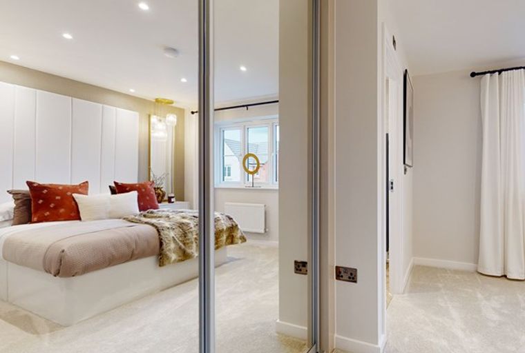 A bedroom with a bed, pillows, a throw blanket, and a mirrored wardrobe.