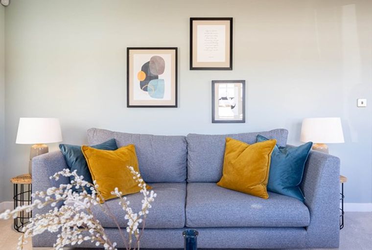 A grey sofa with yellow and blue cushions in a living room.