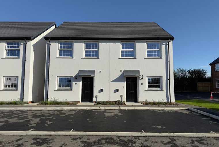 A row of modern white semi-detached houses with dark roofs and black front doors.
