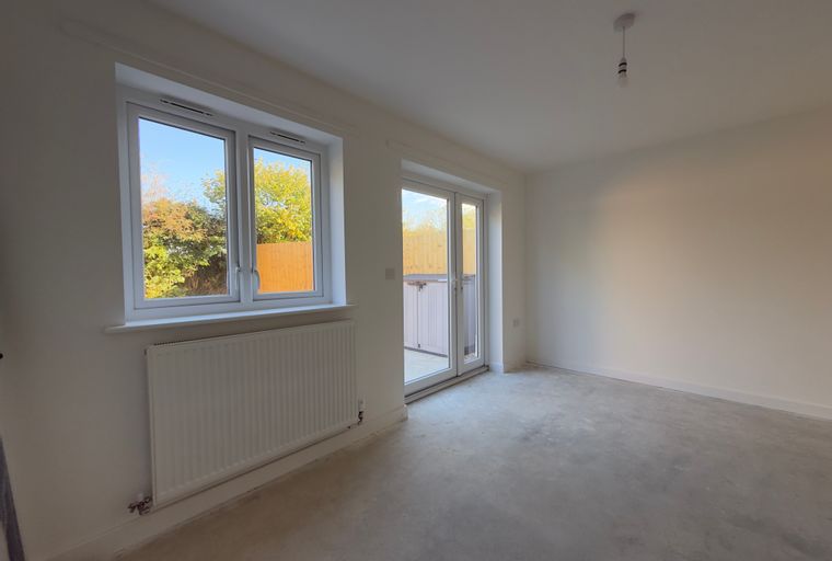 A room with a window, radiator, and double doors.