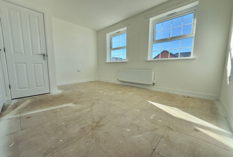 A room with a door, two windows, and a radiator.