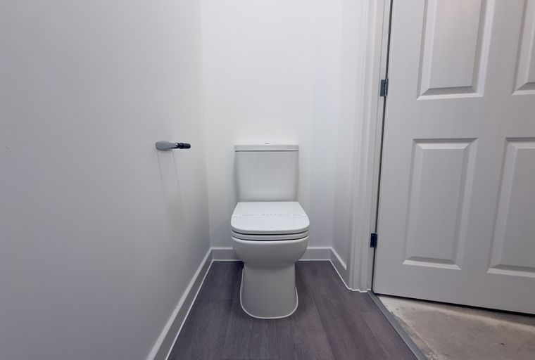 A toilet in a bathroom with a toilet paper holder and a white door.