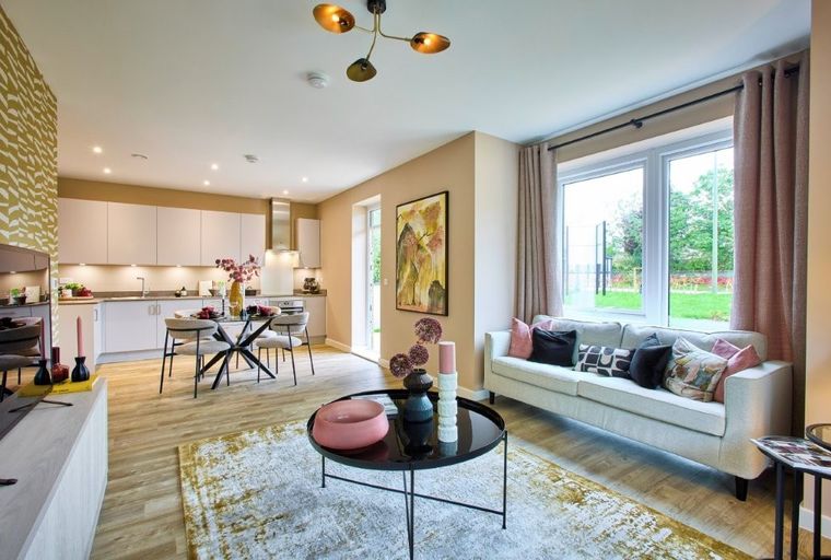 A living room and kitchen area with a sofa, coffee table, dining table, and kitchen cabinets.