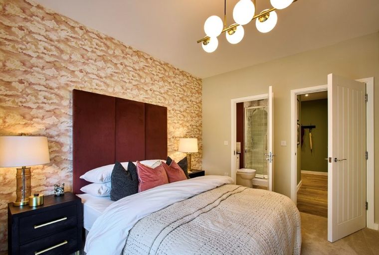 A bedroom with a bed, headboard, bedside tables, and doors leading to other rooms.