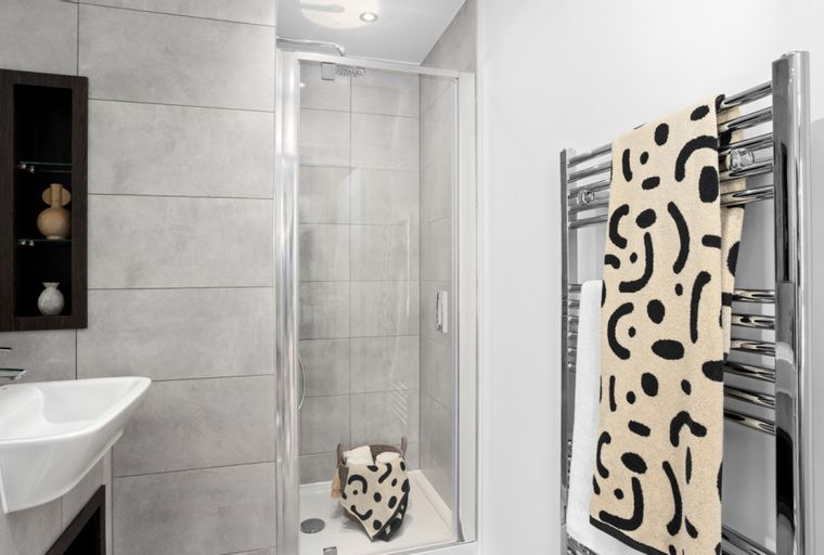 A modern bathroom with a shower enclosure, sink, and towel warmer.