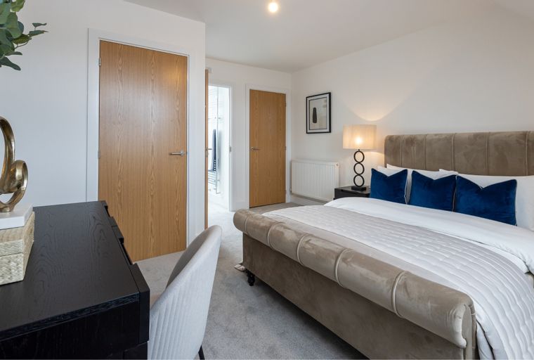 A bedroom with a bed, pillows, and wooden doors.