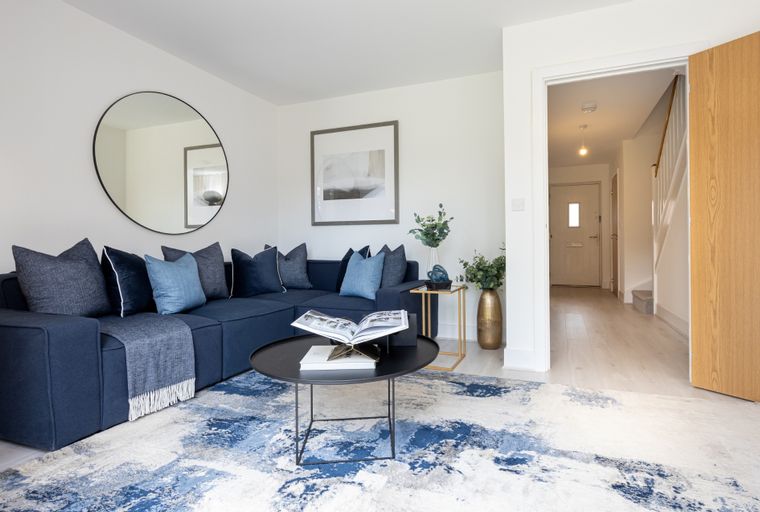 A living room with a navy sectional sofa, a coffee table, and a large abstract rug.