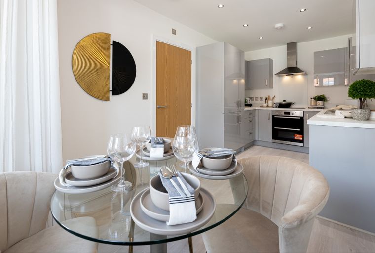 A dining area and kitchen with modern grey cabinets and a glass-top table.