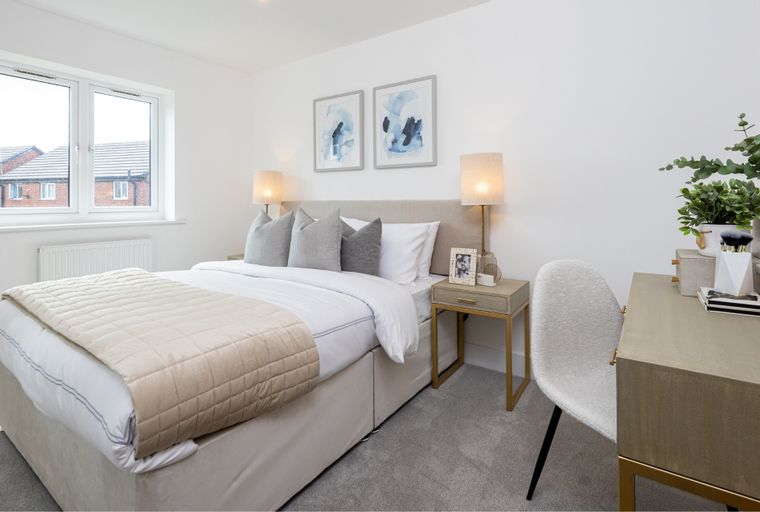 A bedroom with a bed, nightstand, and a vanity.