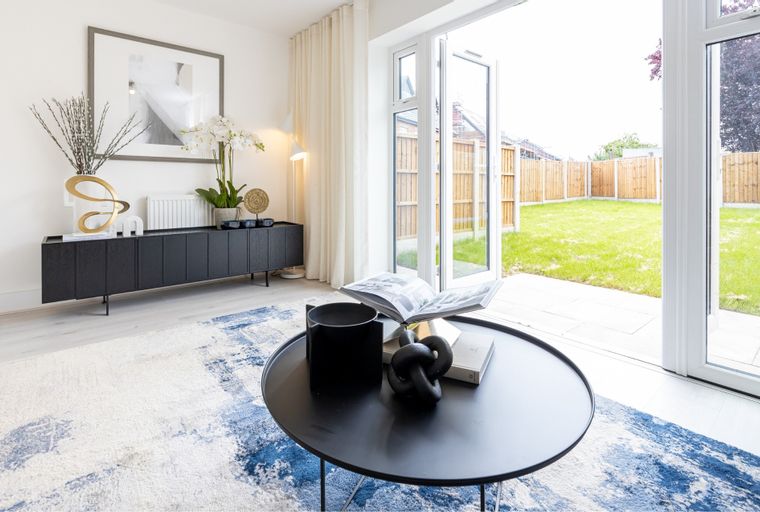 A living room with a black sideboard, a coffee table, and French doors opening to a backyard.