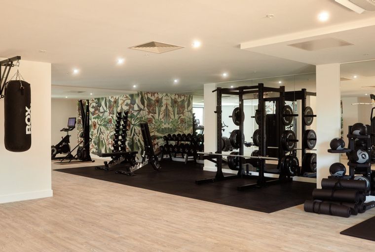 A gym with exercise equipment including a boxing bag, weight rack, dumbbells, and exercise bikes.
