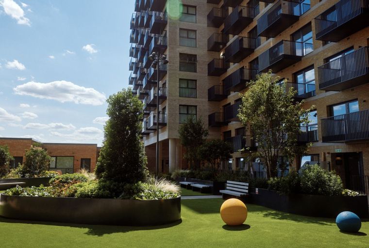 A rooftop garden with modern apartment buildings and outdoor seating.
