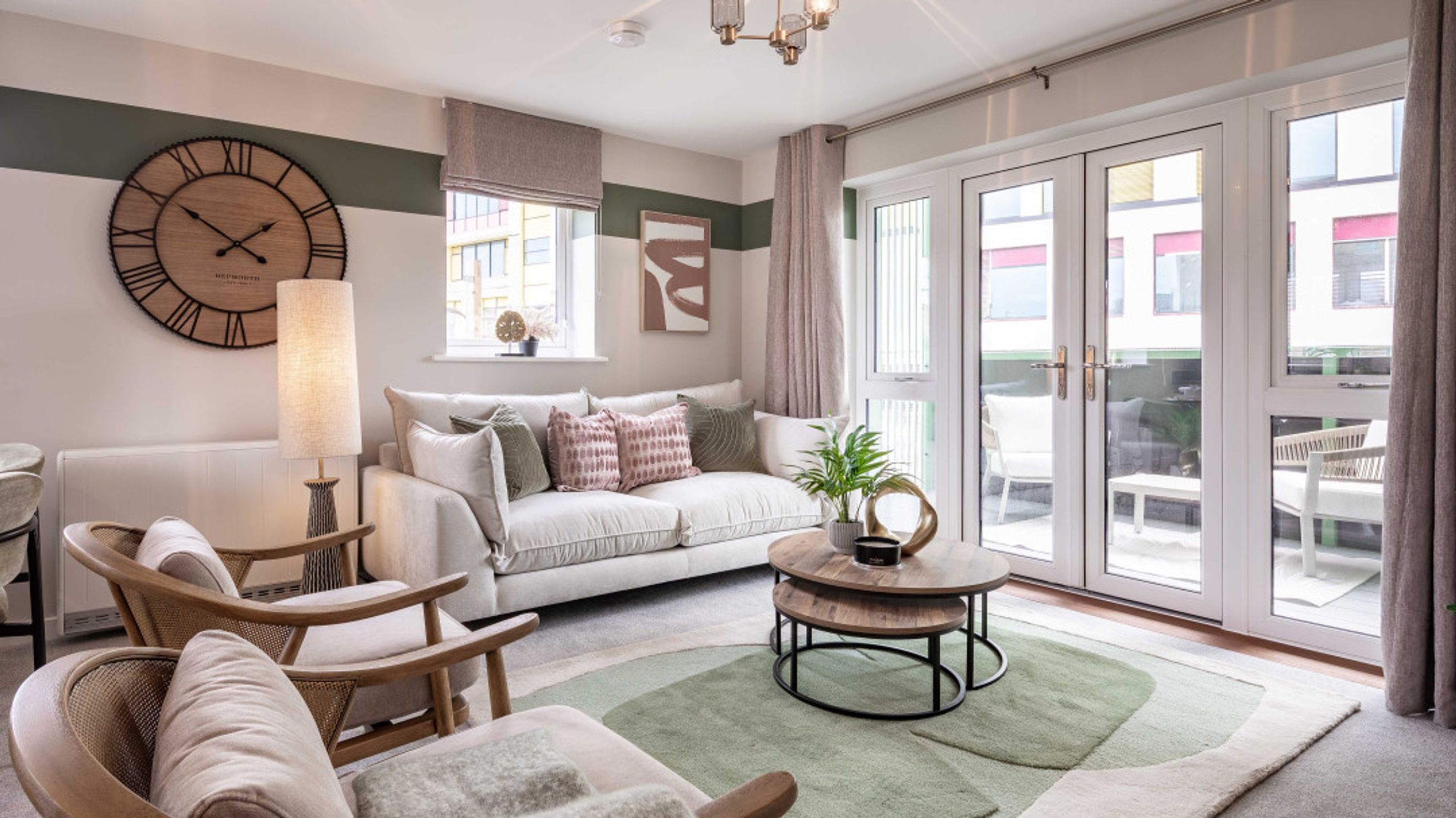 A living room with a sofa, coffee table, chairs, and a large clock on the wall.