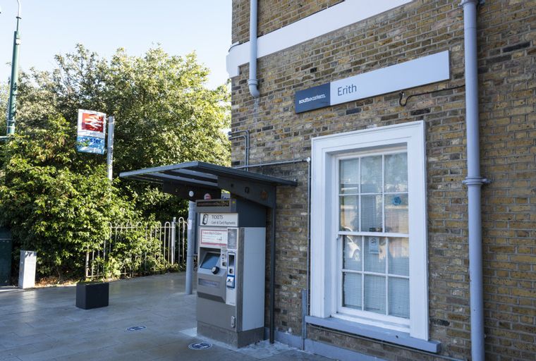 A train station platform with a ticket machine and signage for Erith station.