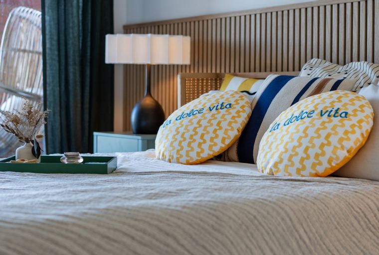 A bedroom with a bed, pillows, a lamp, and a hanging chair.