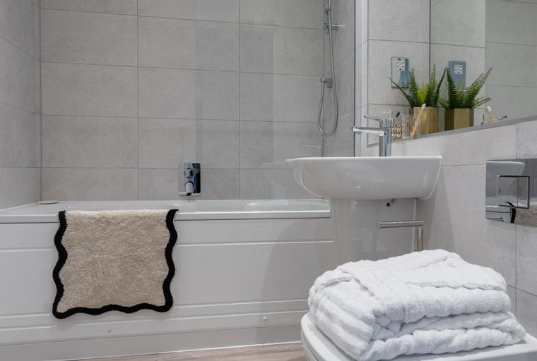 A bathroom with a bathtub, sink, and towels.