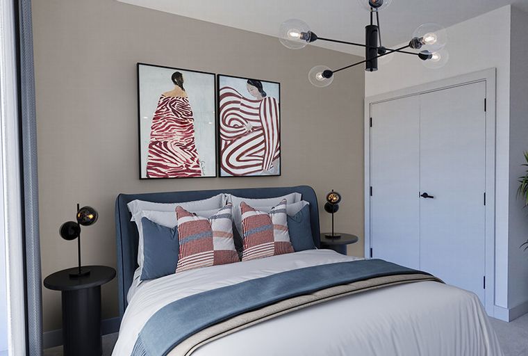 A bedroom with a bed, two paintings, a chandelier, and a closet.