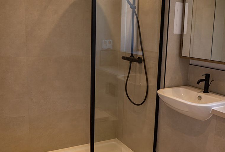 A bathroom with a walk-in shower, a sink, and a medicine cabinet.