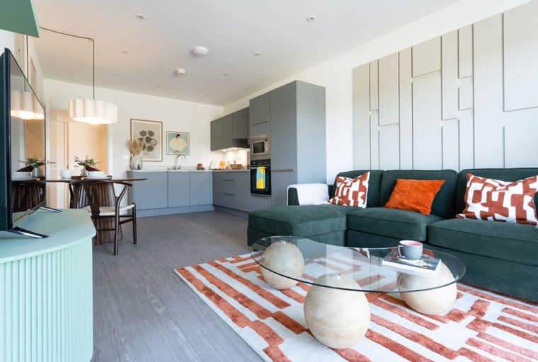 A living room and kitchen area with a sofa, coffee table, and kitchen cabinets.