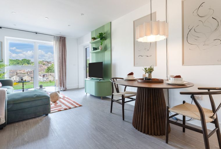 A living and dining area with a sofa, coffee table, dining table, chairs, and a TV unit.