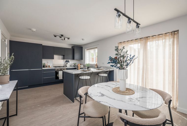 A modern kitchen and dining area with dark cabinets, a marble island, and a dining table.