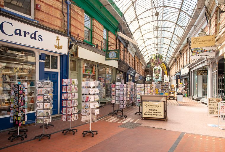 A covered arcade with various shops and displays of greeting cards.