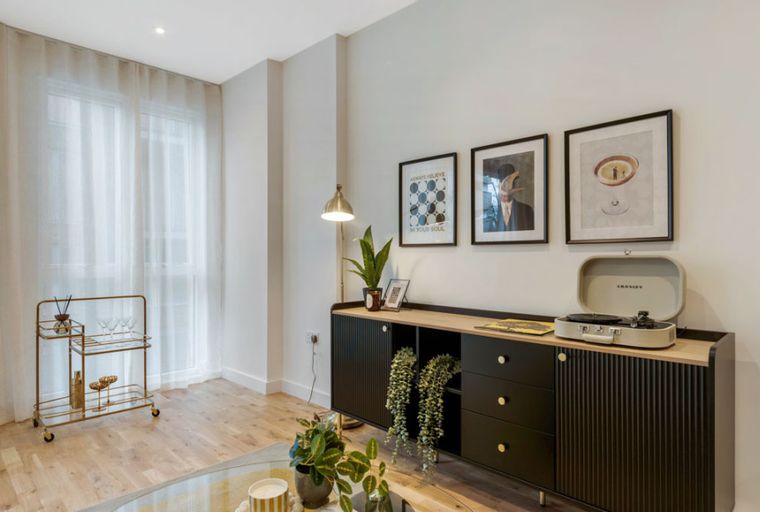A living room with a sideboard, record player, bar cart, and artwork.