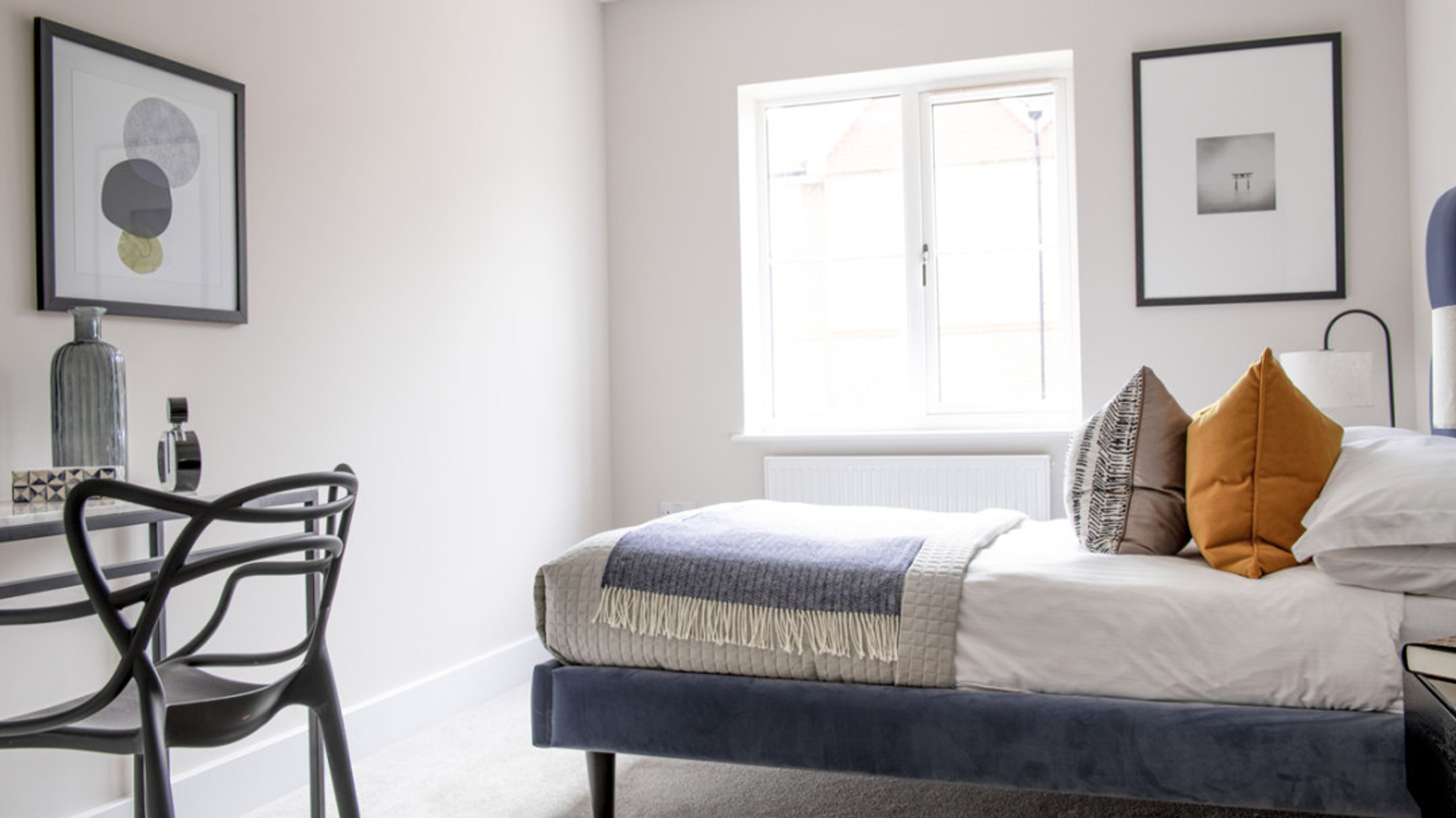A bedroom with a bed, desk, chair, and window.
