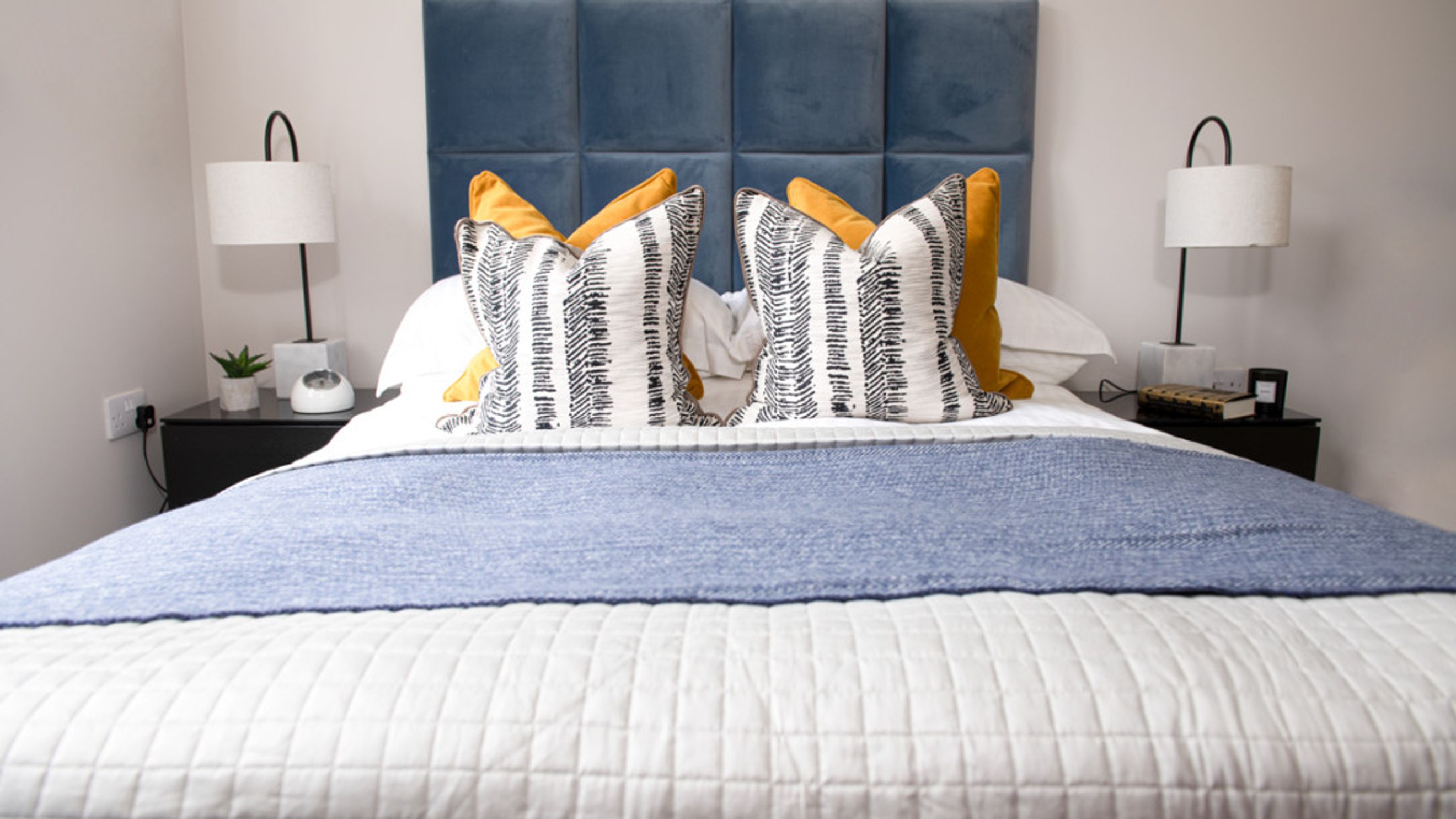A bedroom with a bed, pillows, and bedside tables.