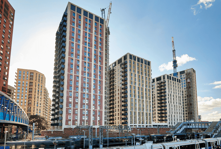 A cityscape with modern high-rise buildings and cranes under a blue sky.