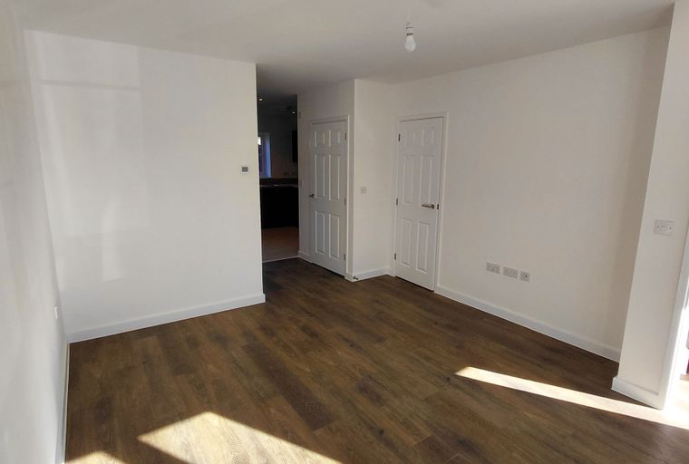 A living room with wood-effect flooring and white walls.