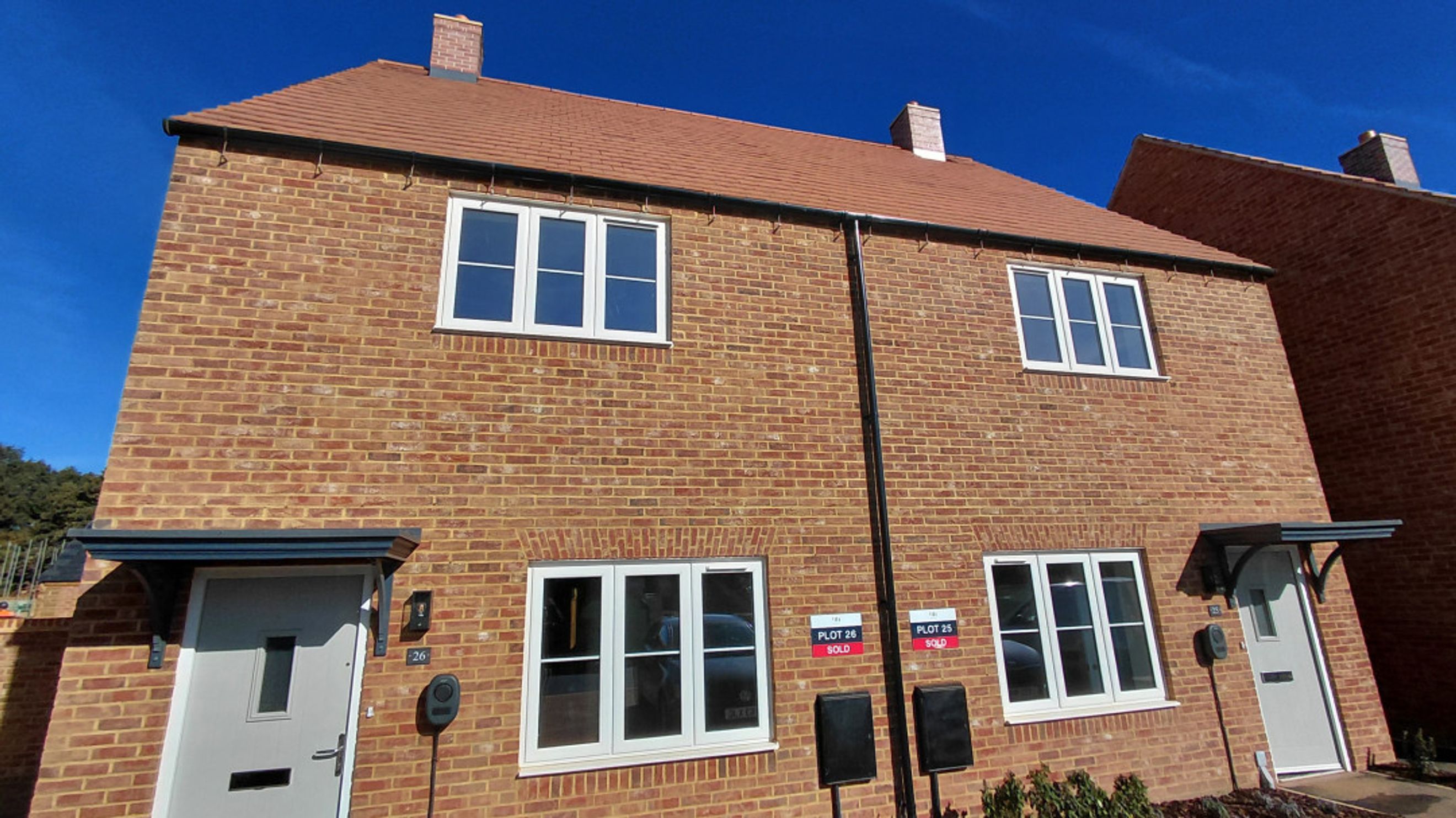 A new build semi-detached house with brick exterior and white-framed windows.