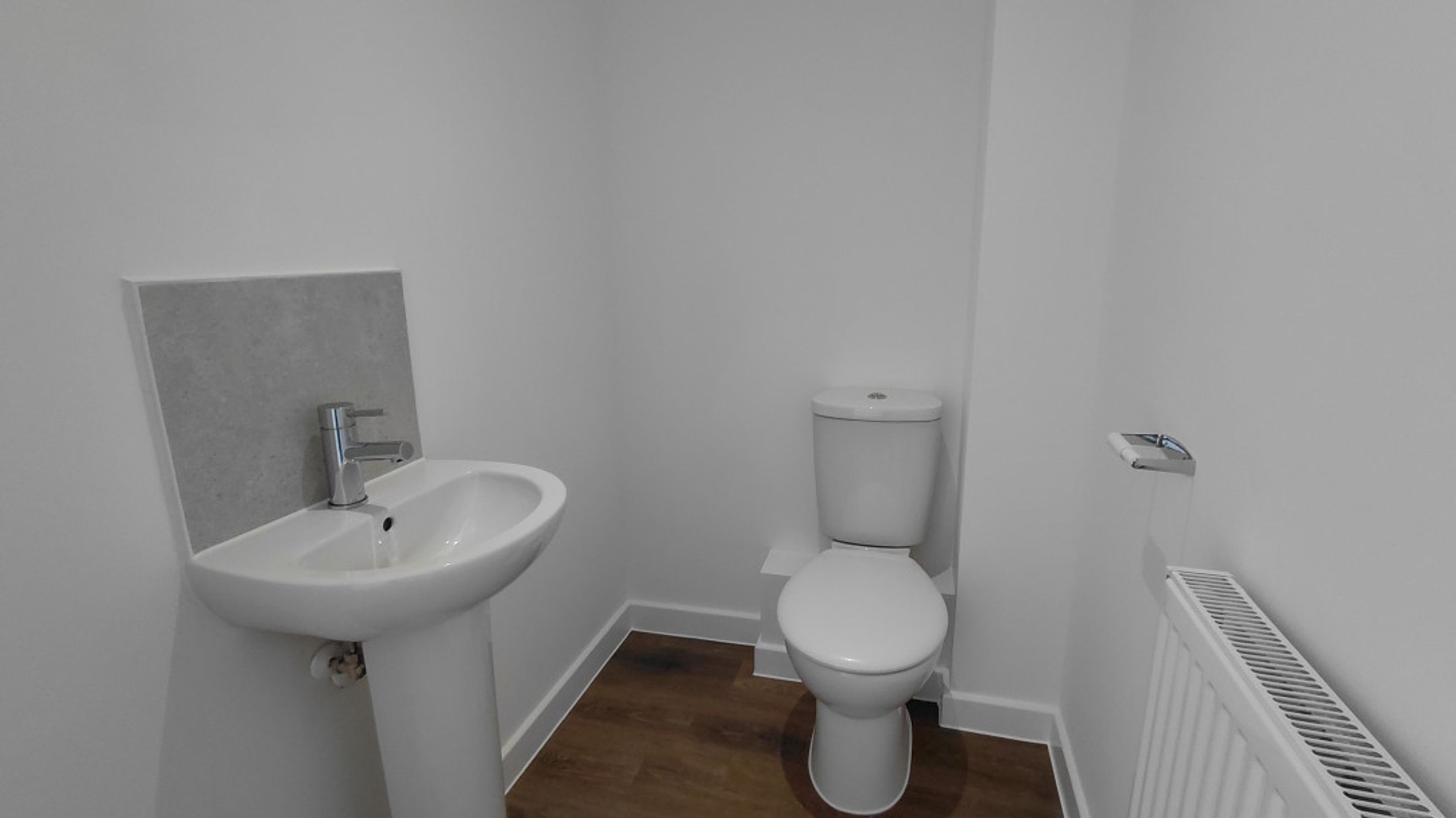 A bathroom with a sink, toilet, and radiator.