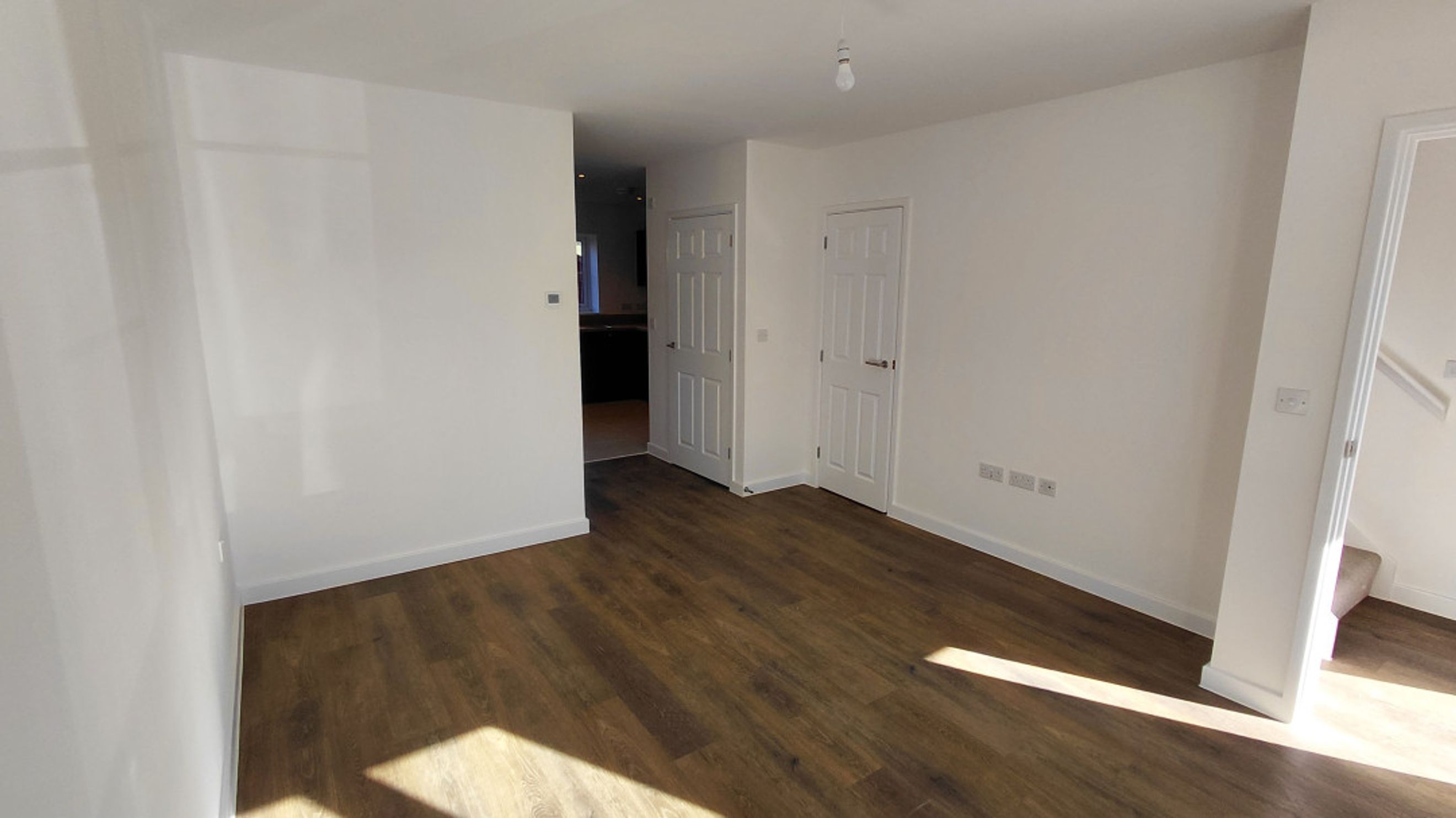 A living room with wood-effect flooring and white walls.