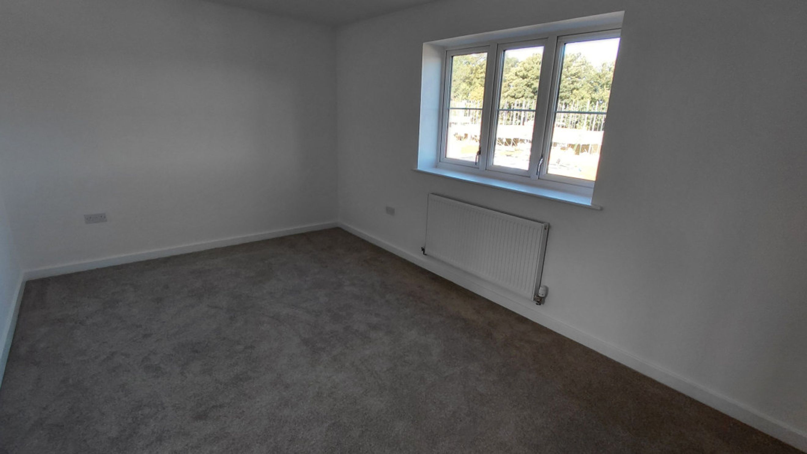 A bedroom with a window and a radiator.