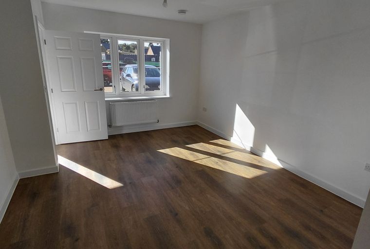 A room with a white door, a window, and wood-effect flooring.
