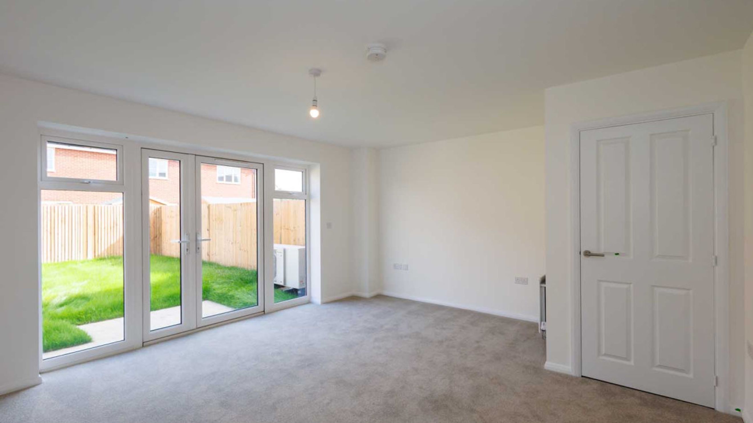 A living room with double doors leading to a garden and an interior door.
