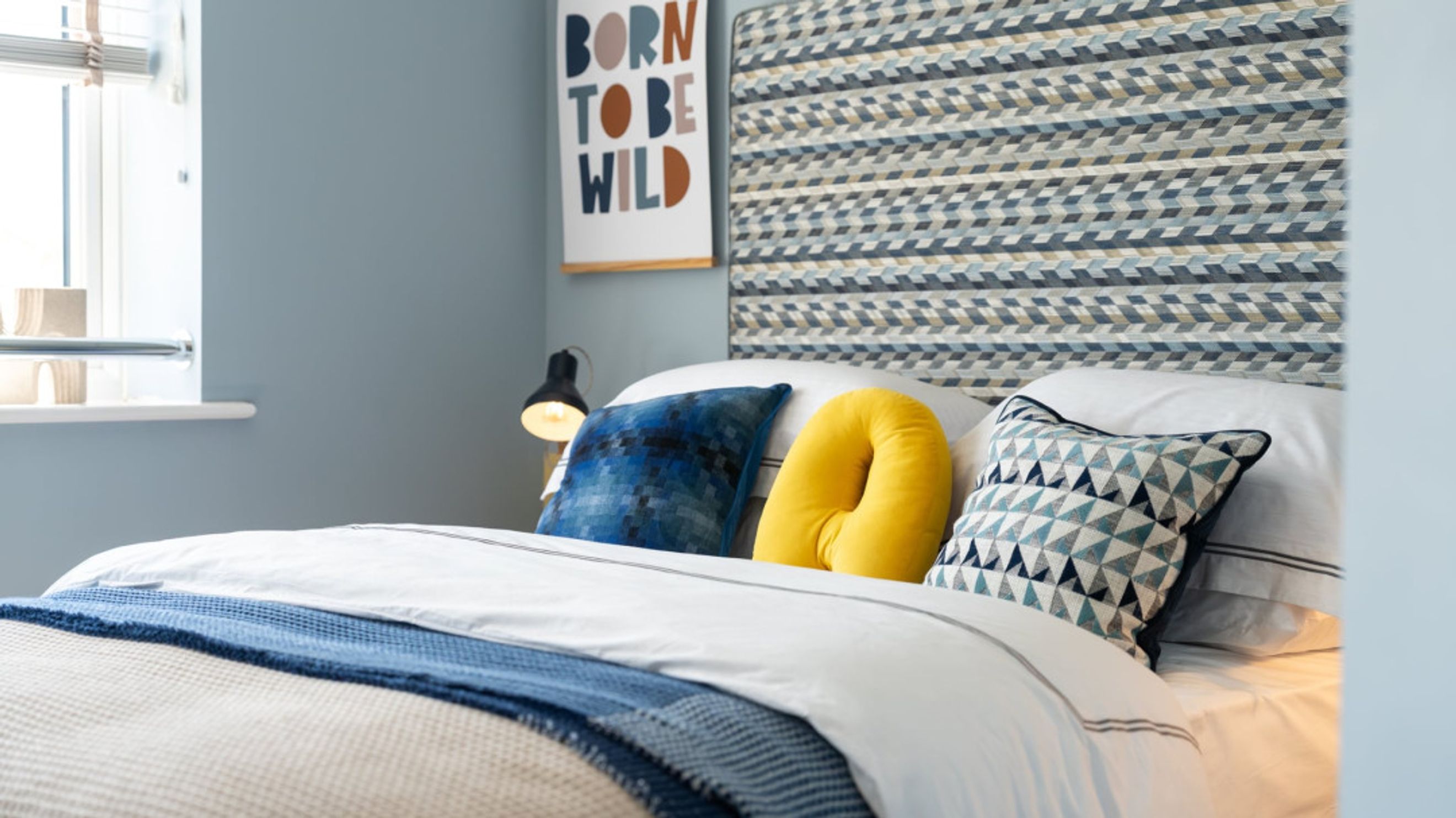 A bedroom with a bed, pillows, and a headboard.