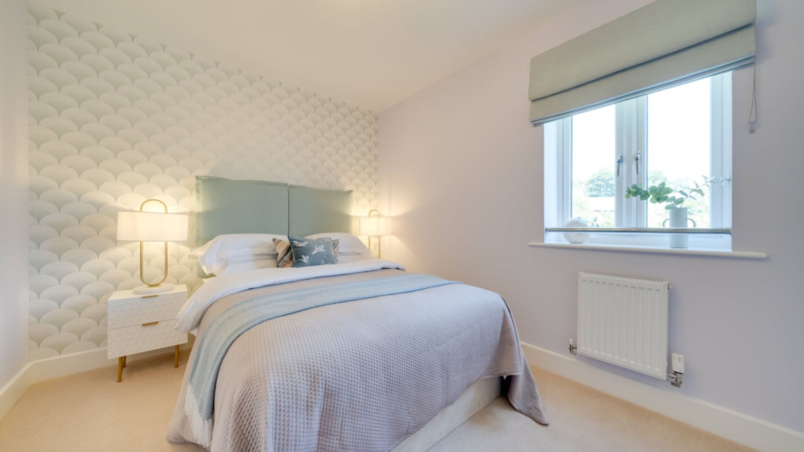 A bedroom with a bed, bedside tables, lamps, and a window.