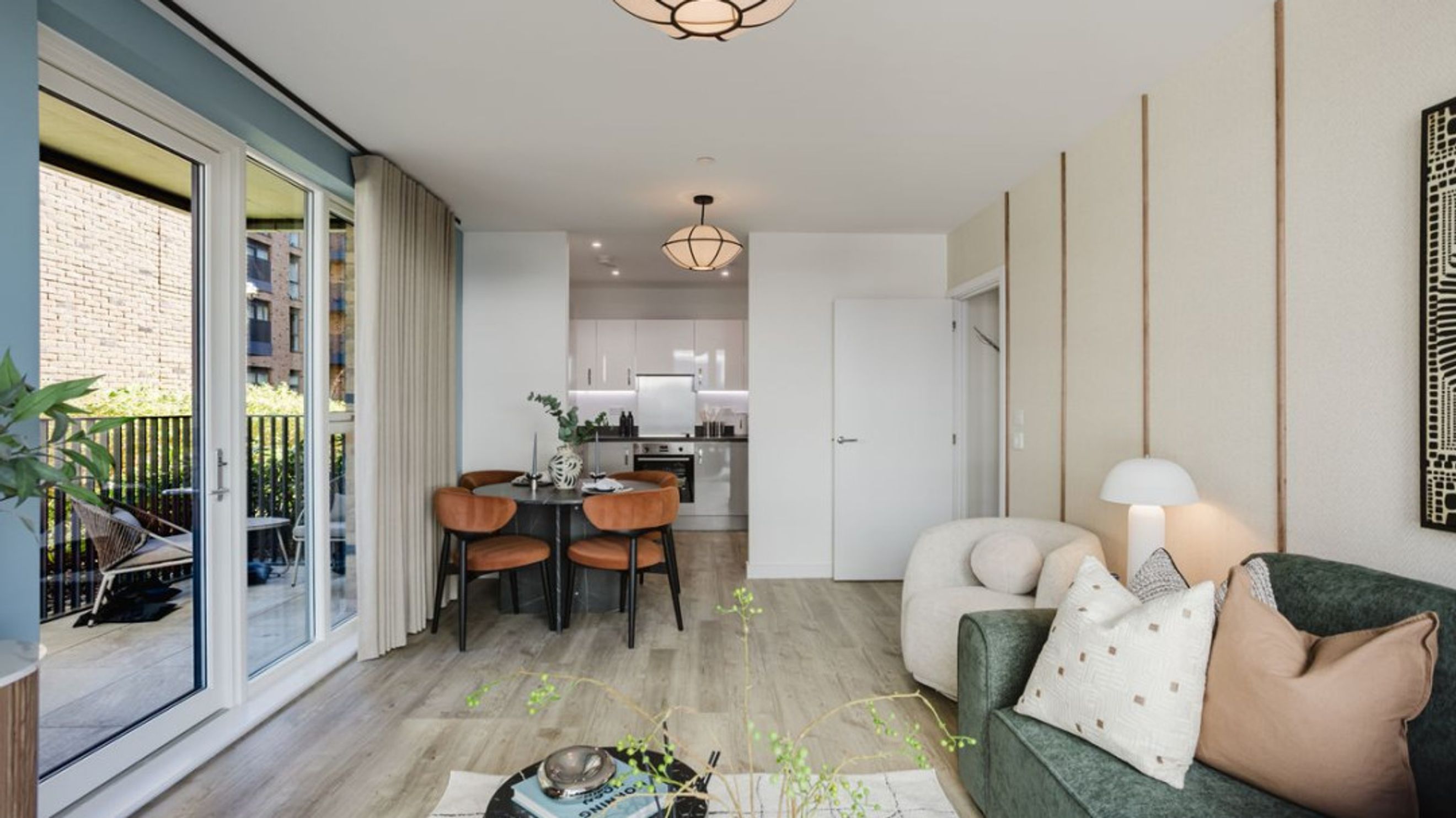 A living room and dining area with a kitchen in the background, featuring a sofa, chairs, and a table.