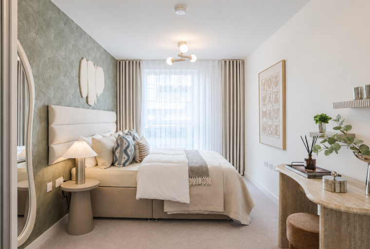 A bedroom with a bed, bedside tables, a vanity, and artwork.