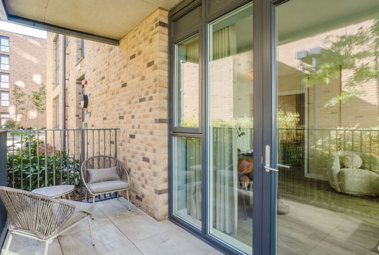 A balcony with two chairs and a small table.