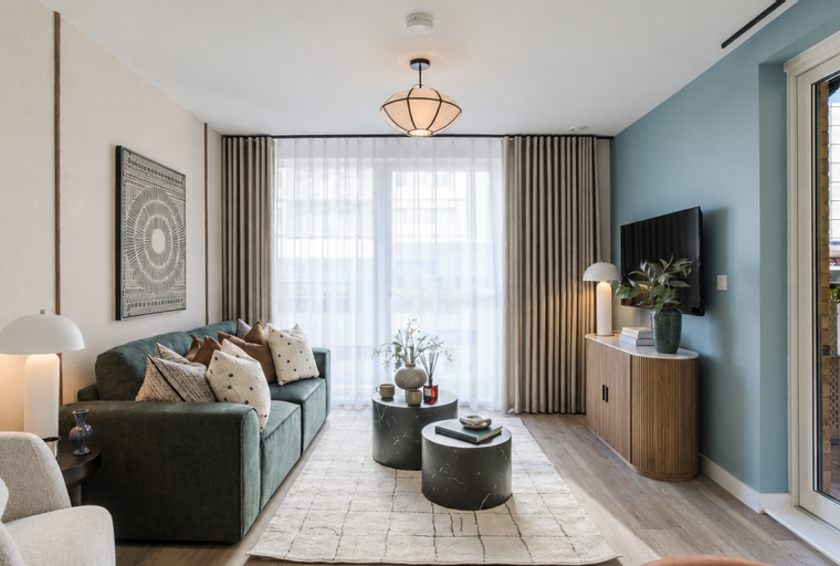 A living room with a green sofa, coffee tables, and a television.