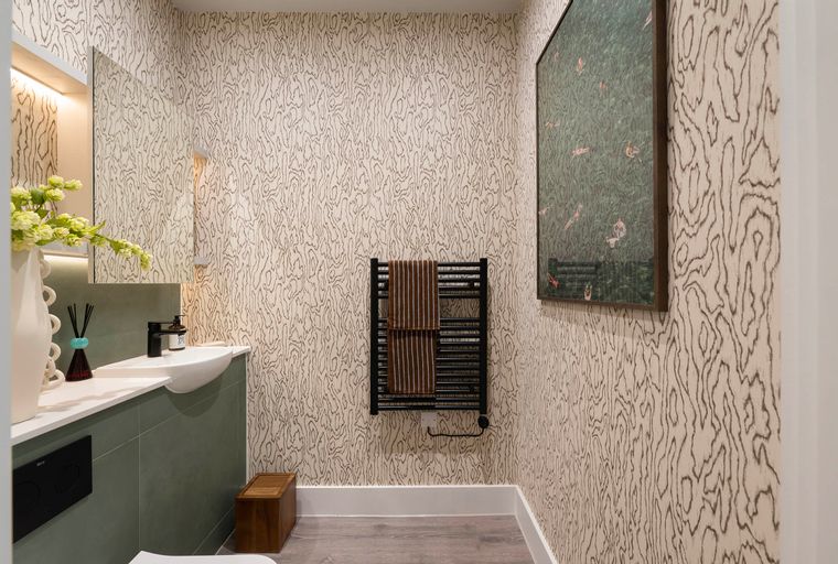 A bathroom with a sink, a towel rack, and patterned wallpaper.