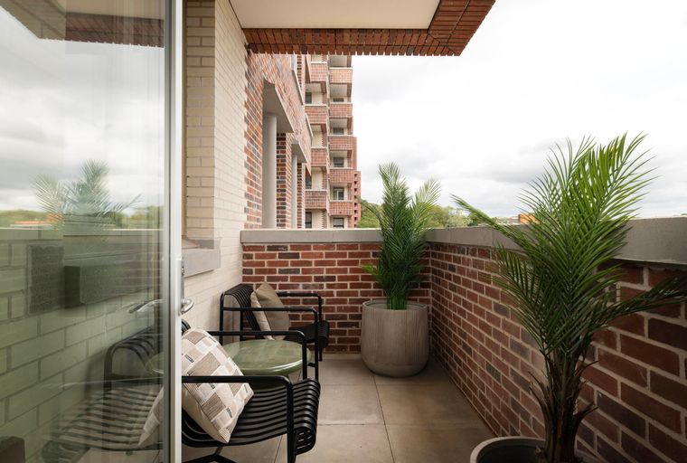 A balcony with two chairs, a table, and potted plants.