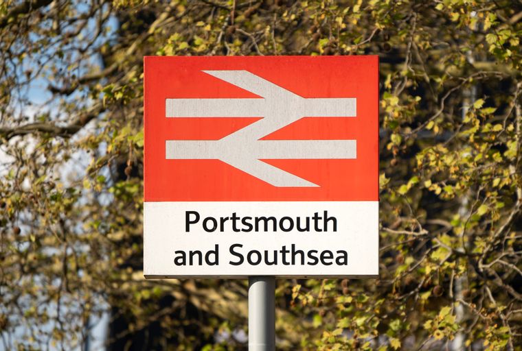 A sign for Portsmouth and Southsea train station with the national rail logo.